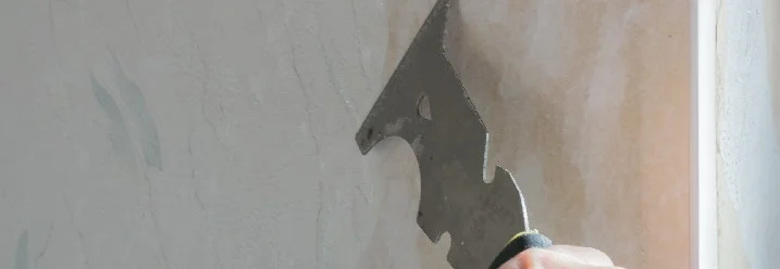 Hand entfernt Tapetenstücke mit Spachtel